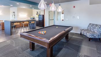 a billiards table in a clubhouse with a bar and a pool table
